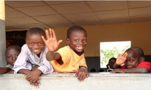 Four kids from Mali, Africa waving and smiling. Denik, Packed with Purpose Impact Partners.
