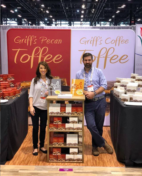 Griff's Toffee team next to their product at an exposition. Packed with Purpose Impact Partners.