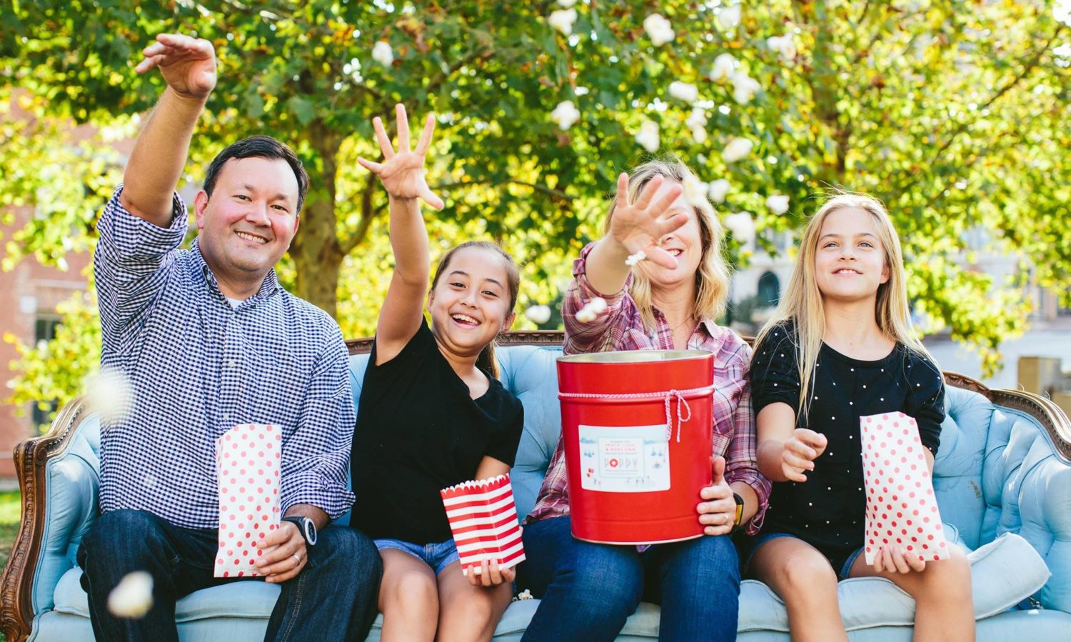 Family sitting and throwing popcorn from Poppy Handcrafted Popcorn, Packed with Purpose Impact Partners