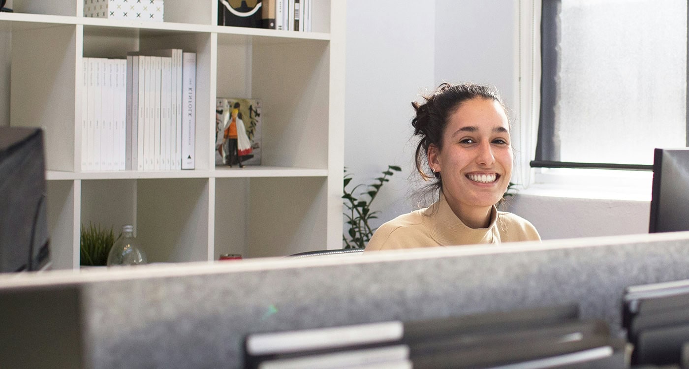 Smiling admin professional seated at a desk in a modern, well-lit office space