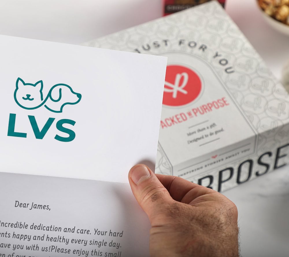 An employee holding a customized message card in from of a gift box