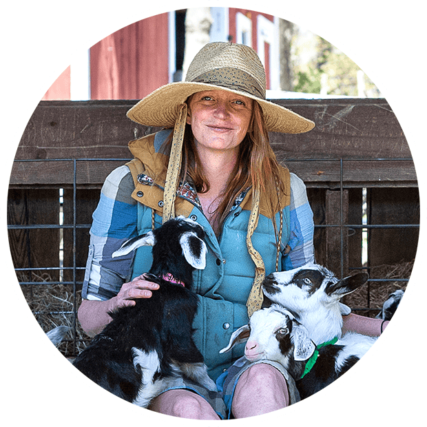 Smiling woman on a farm with goats