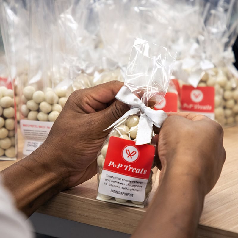 Hands assembling PwP white pretzel ball packaging