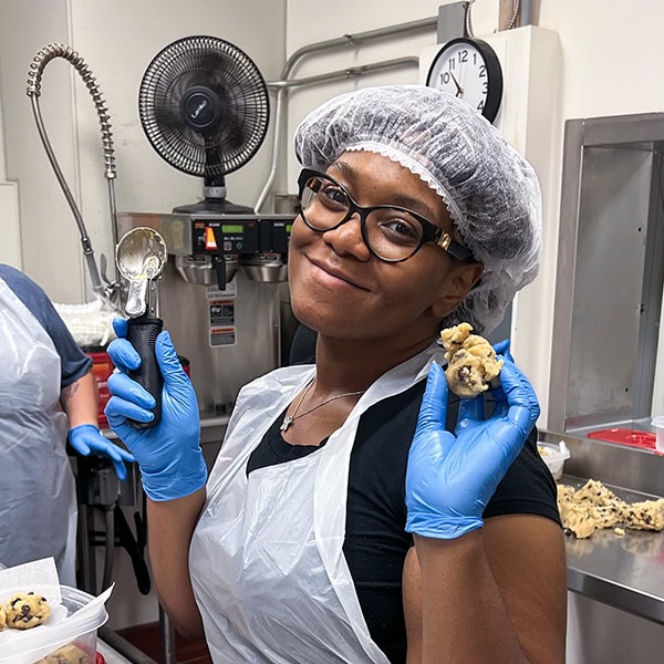 Women posing with cookie dough while making cookies