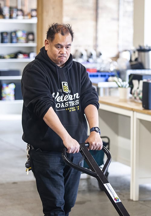 Veteran man pulling a palette of coffee beans