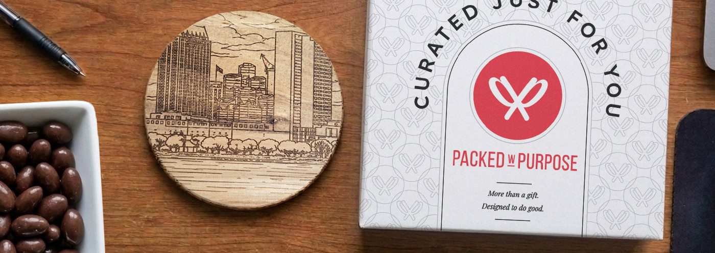Packed with Purpose gift box and personalized coaster on an office desk with chocolate almonds