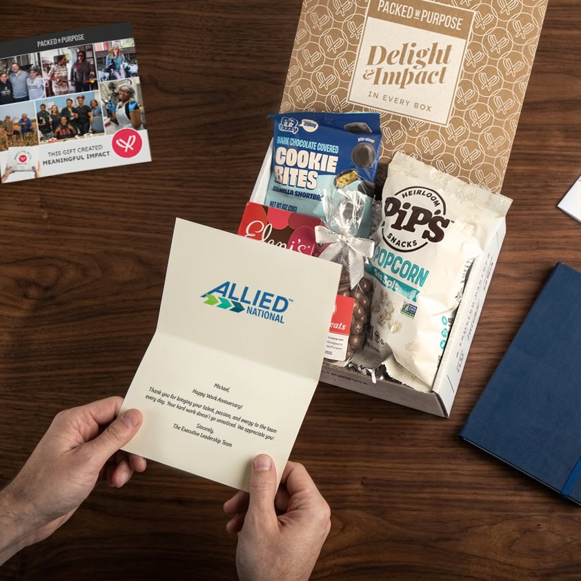 An employee reading a message card with an open gift on their desk in the background