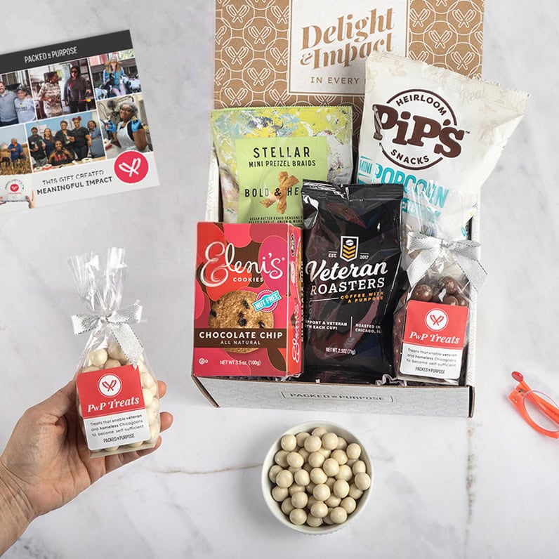 Open gift on a marble desktop with an employee holding a bag of PwP Treats