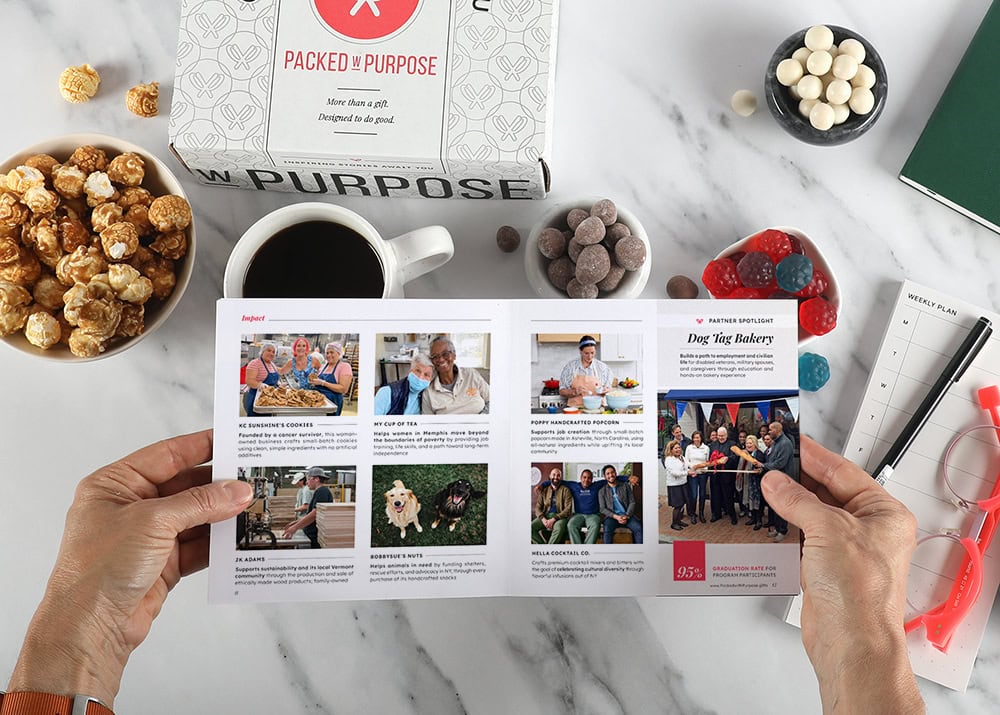 Hands holding an open Impact Booklet above a Packed with Purpose gift