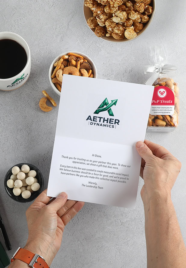 Hands holding a branded message card with a personalized message over a gift