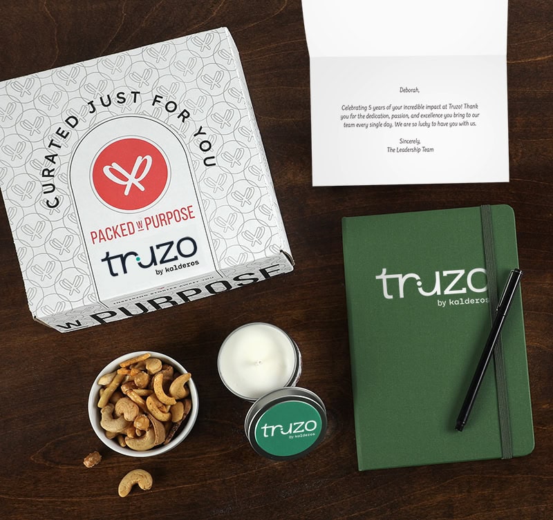 A branded gift box, notebook, candle, and personalized message card